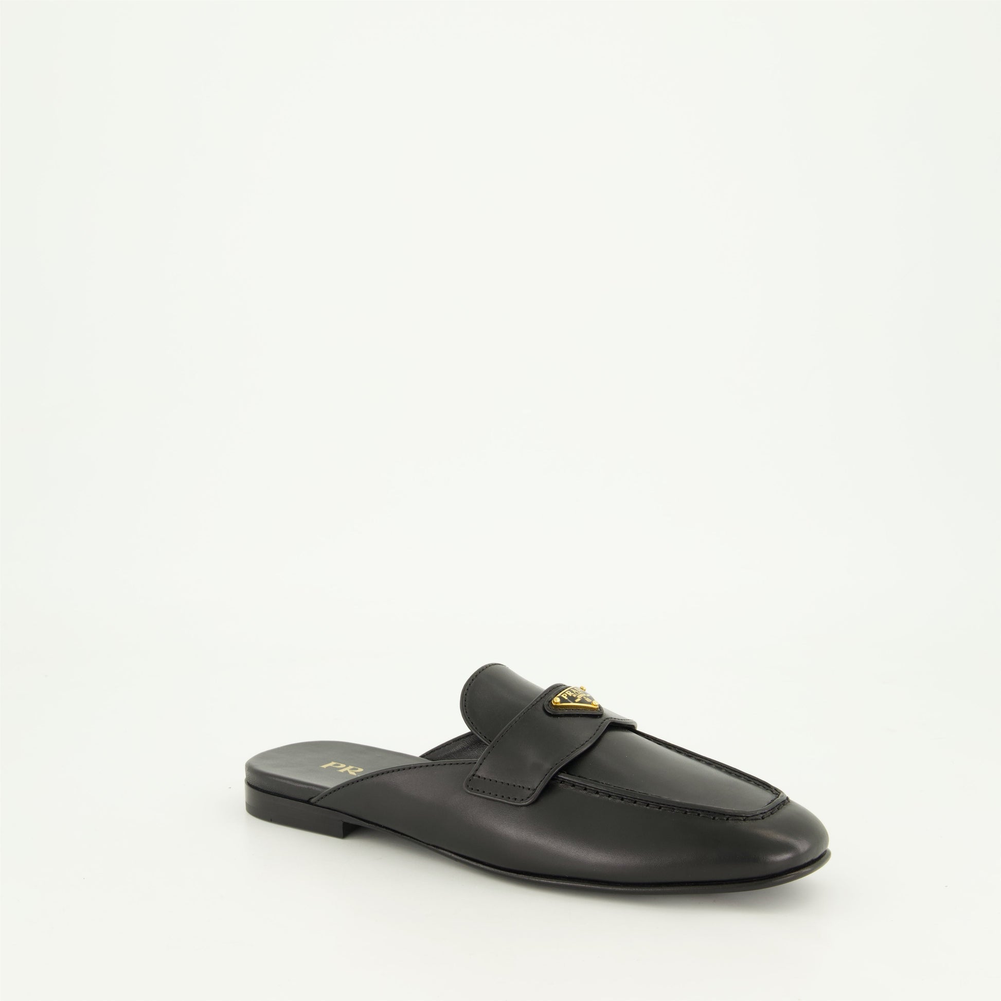 black leather mules, slip-on mules, metal logo mules, amande-shaped toe footwear, monobloc sole shoes