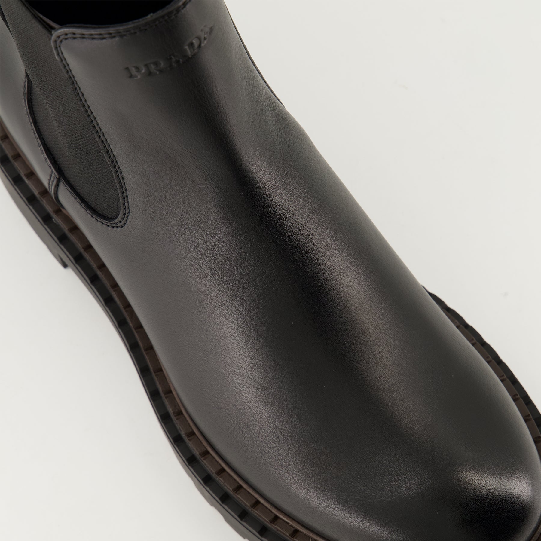 black leather boots, slip-on boots, embossed logo, textured sole, elastic panels