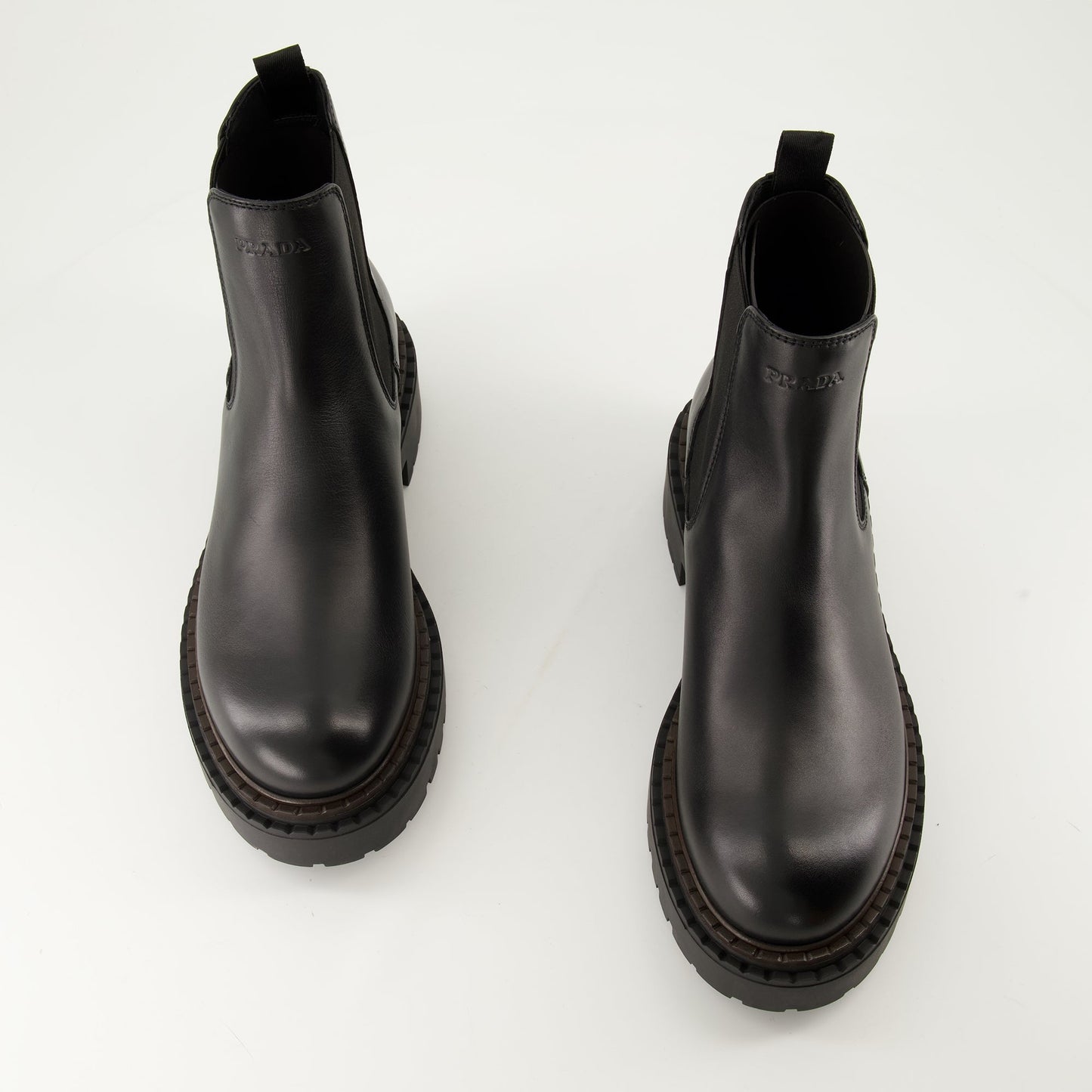 black leather boots, slip-on boots, embossed logo, textured sole, elastic panels