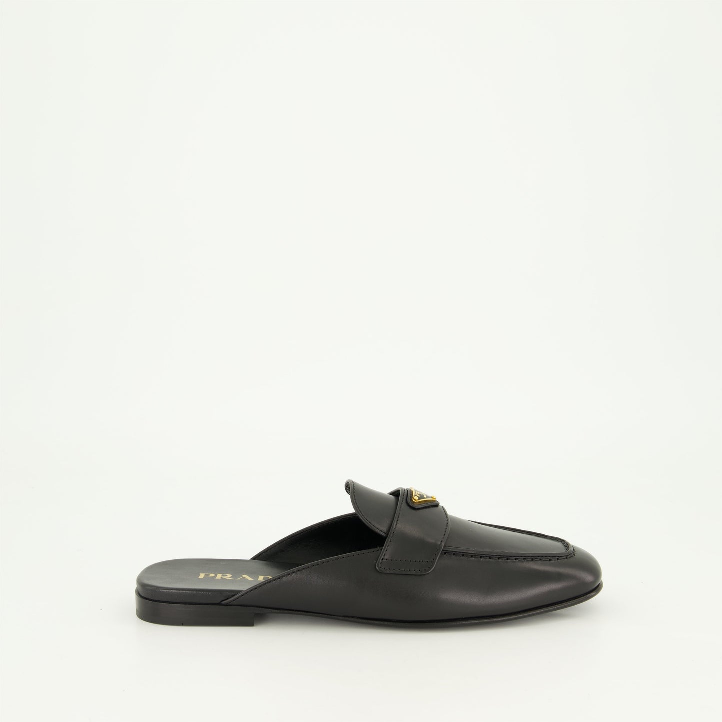 black leather mules, slip-on mules, metal logo mules, amande-shaped toe footwear, monobloc sole shoes